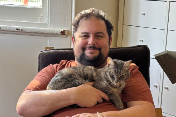 A man sitting in a chair holding a cat
